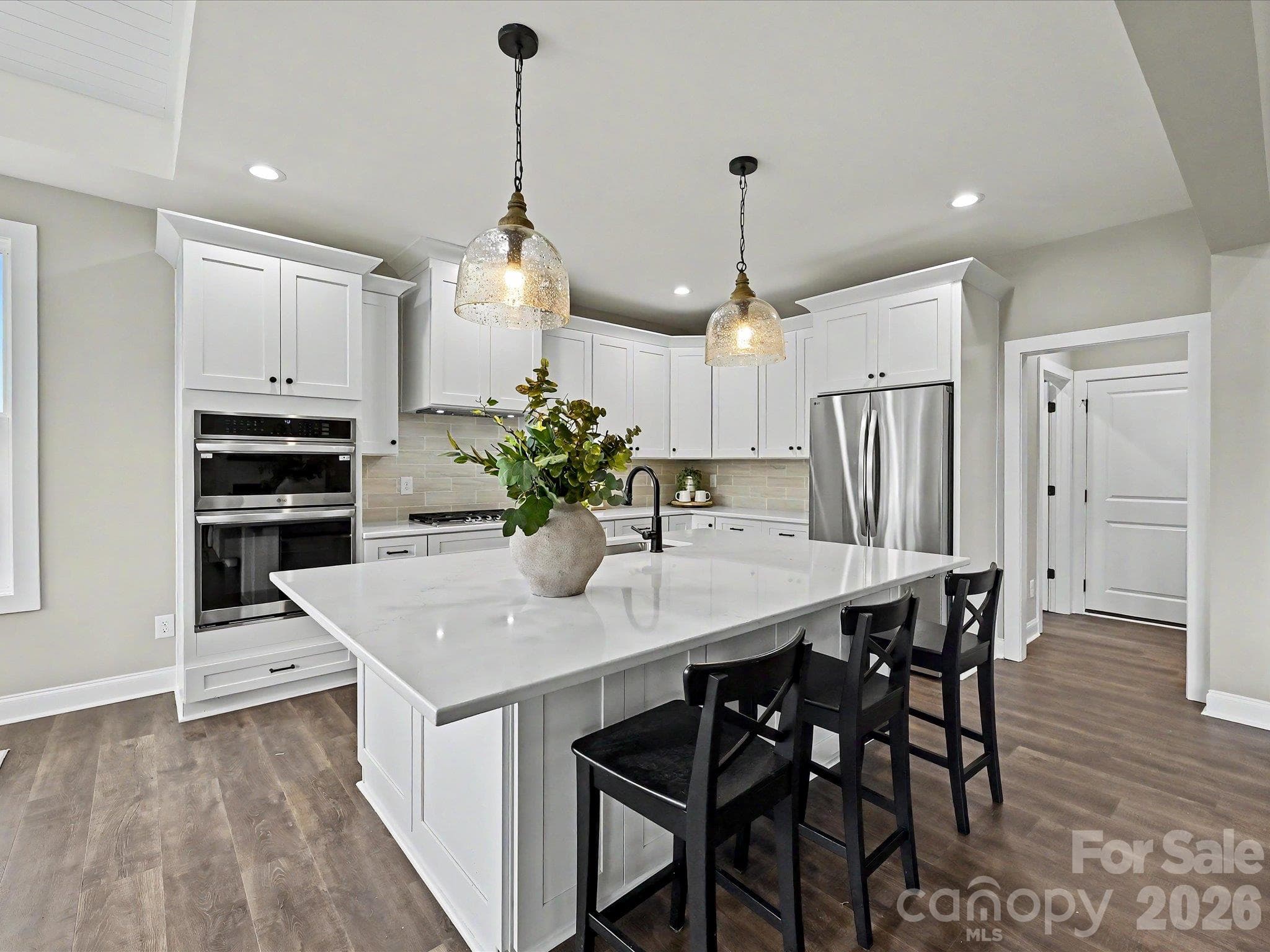 Designer kitchen features a massive quartz island, custom cabinetry, stainless steel appliances & an open layout perfect for everyday living & entertaining. - 159 Lone Pine Road, Statesville