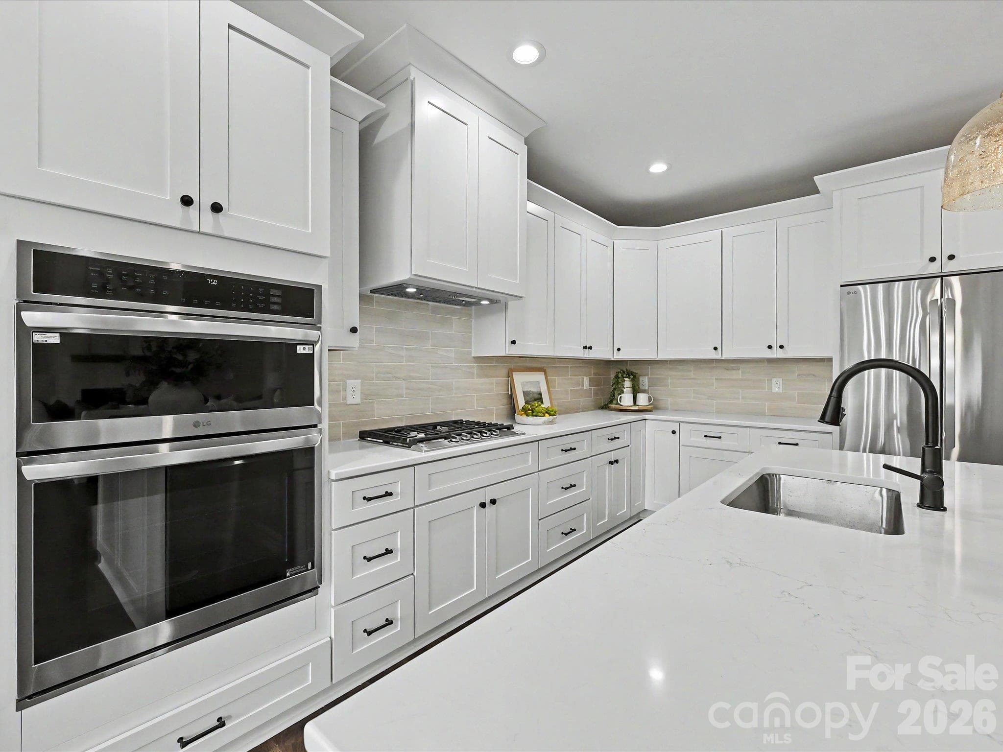 Bright & beautifully designed, this chef's kitchen features quartz counters, custom white cabinetry, stainless steel appliances & a large center island overlooking the open concept living space. - 159 Lone Pine Road, Statesville