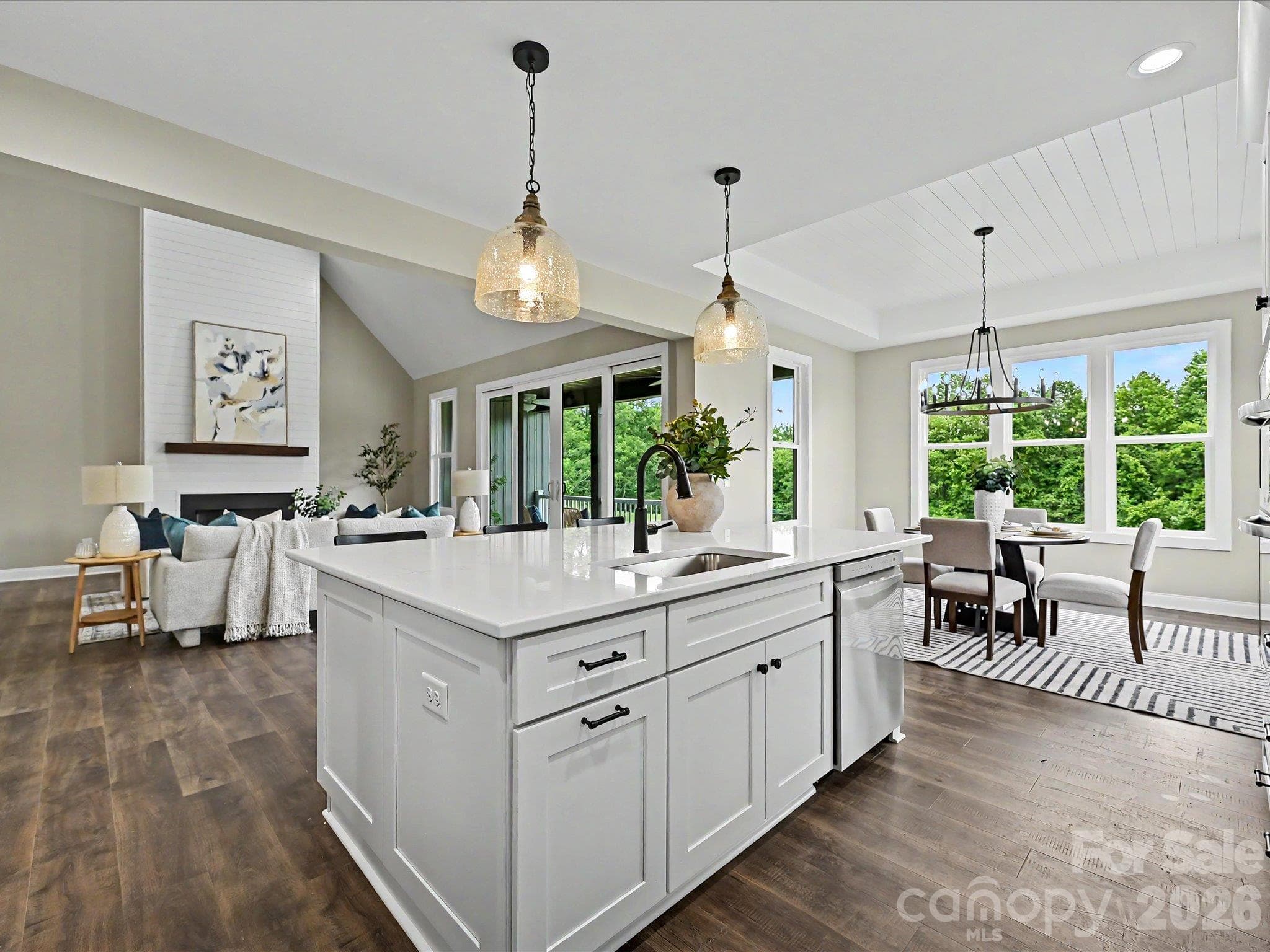 Bright & beautifully designed, this chef's kitchen features quartz counters, custom white cabinetry, stainless steel appliances & a large center island overlooking the open concept living space. - 159 Lone Pine Road, Statesville