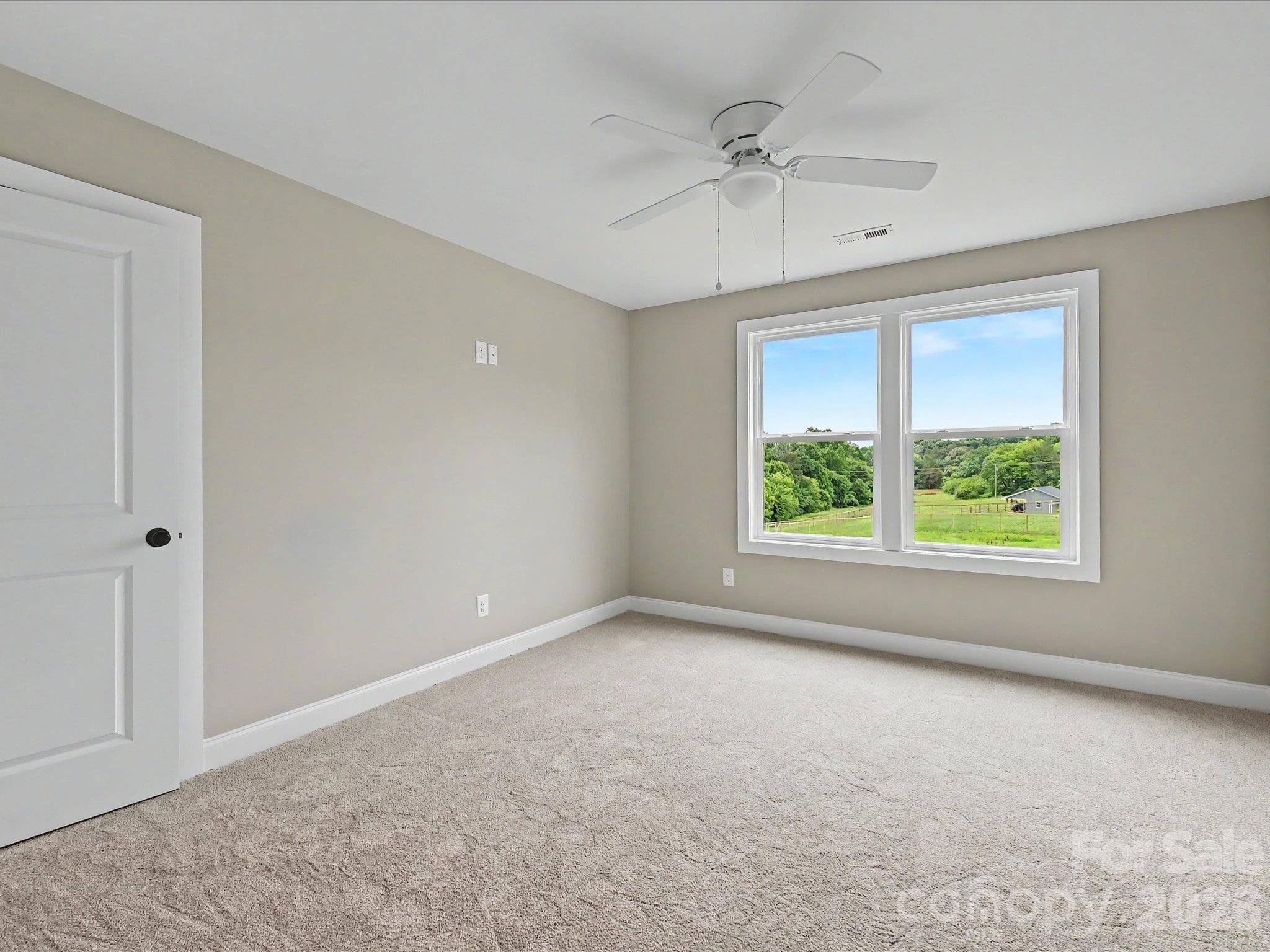 Bright secondary bedroom on upper level features soft carpeting, ceiling fan & large windows showcasing scenic countryside views. - 159 Lone Pine Road, Statesville