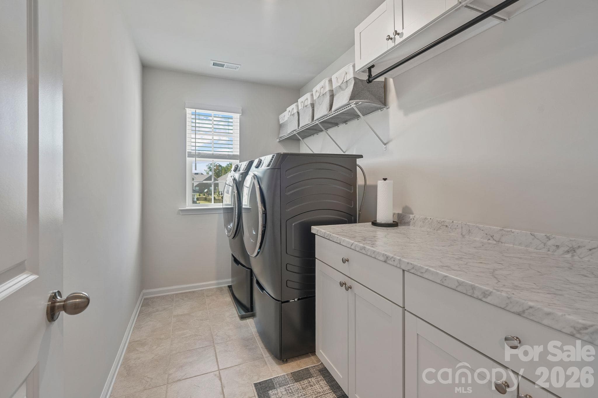 Oversized second-floor laundry room conveniently located between bedrooms, featuring custom cabinetry and ample space for folding laundry. - 107 Hollywood Court, Troutman