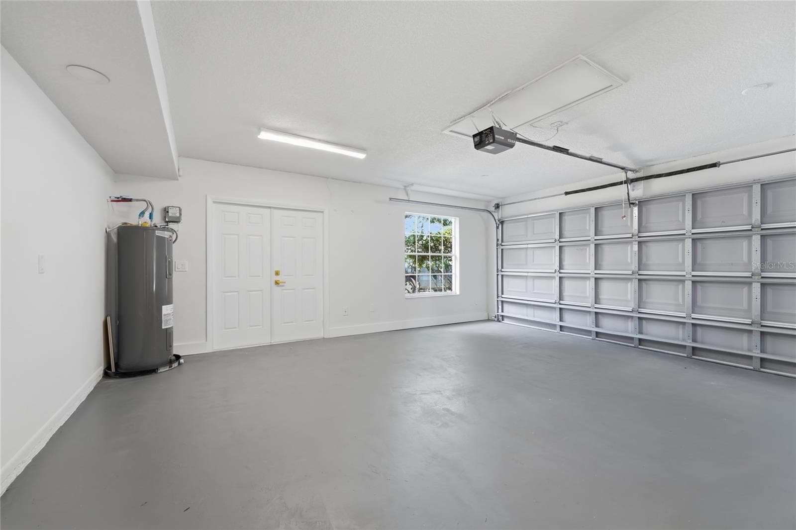 Spacious garage with generous parking space, windows for natural light, and a dedicated exit door. - 13044 BELLERIVE LN, ORLANDO
