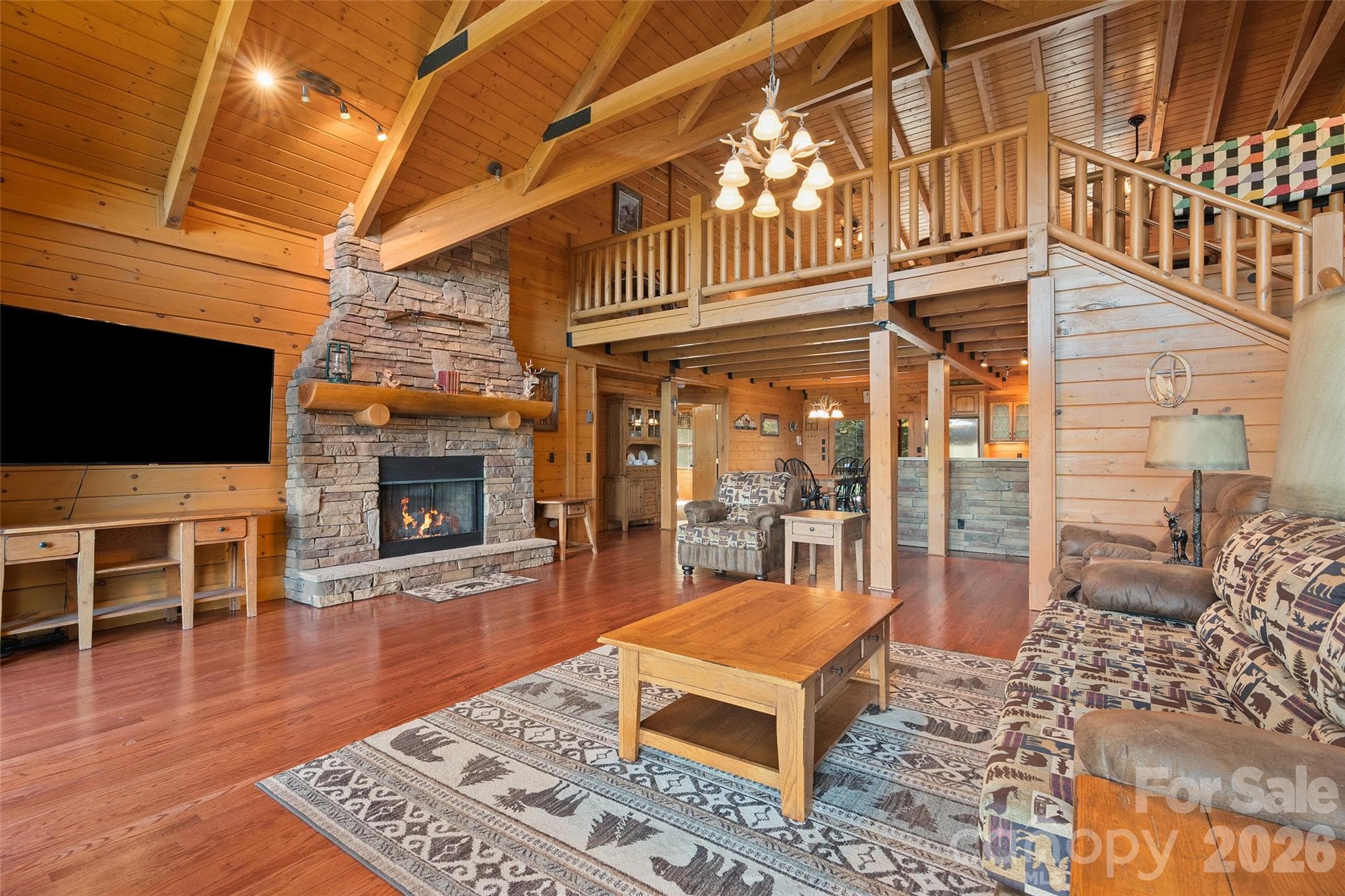 Magnificent great room featuring soaring ceilings, exposed beams, and a stone fireplace. - 124 Borges Lane, Waynesville