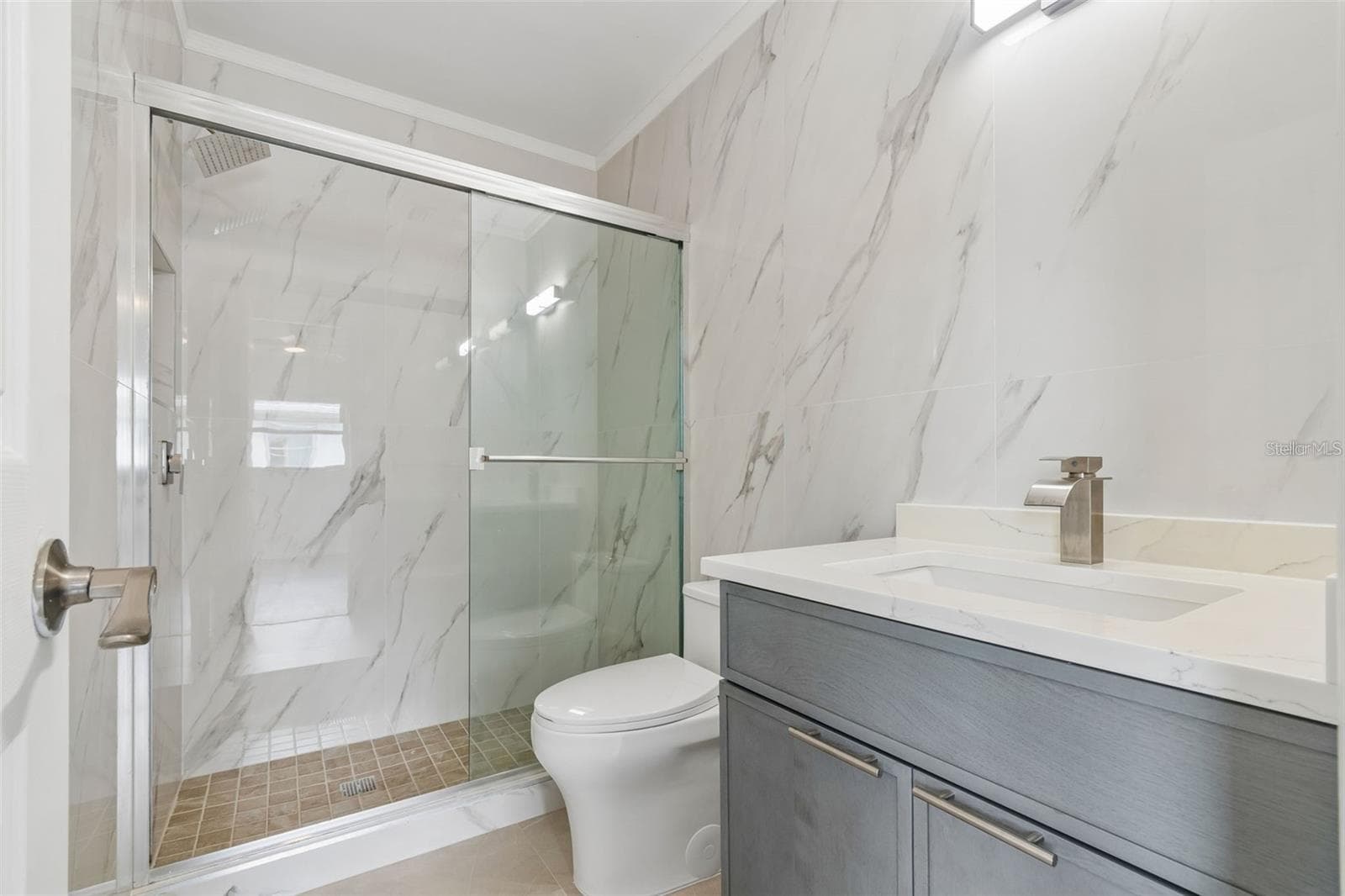 beautiful updated primary bathroom , featuring marble tile and spacious walk in shower - 1023 DEER RUN, VENICE