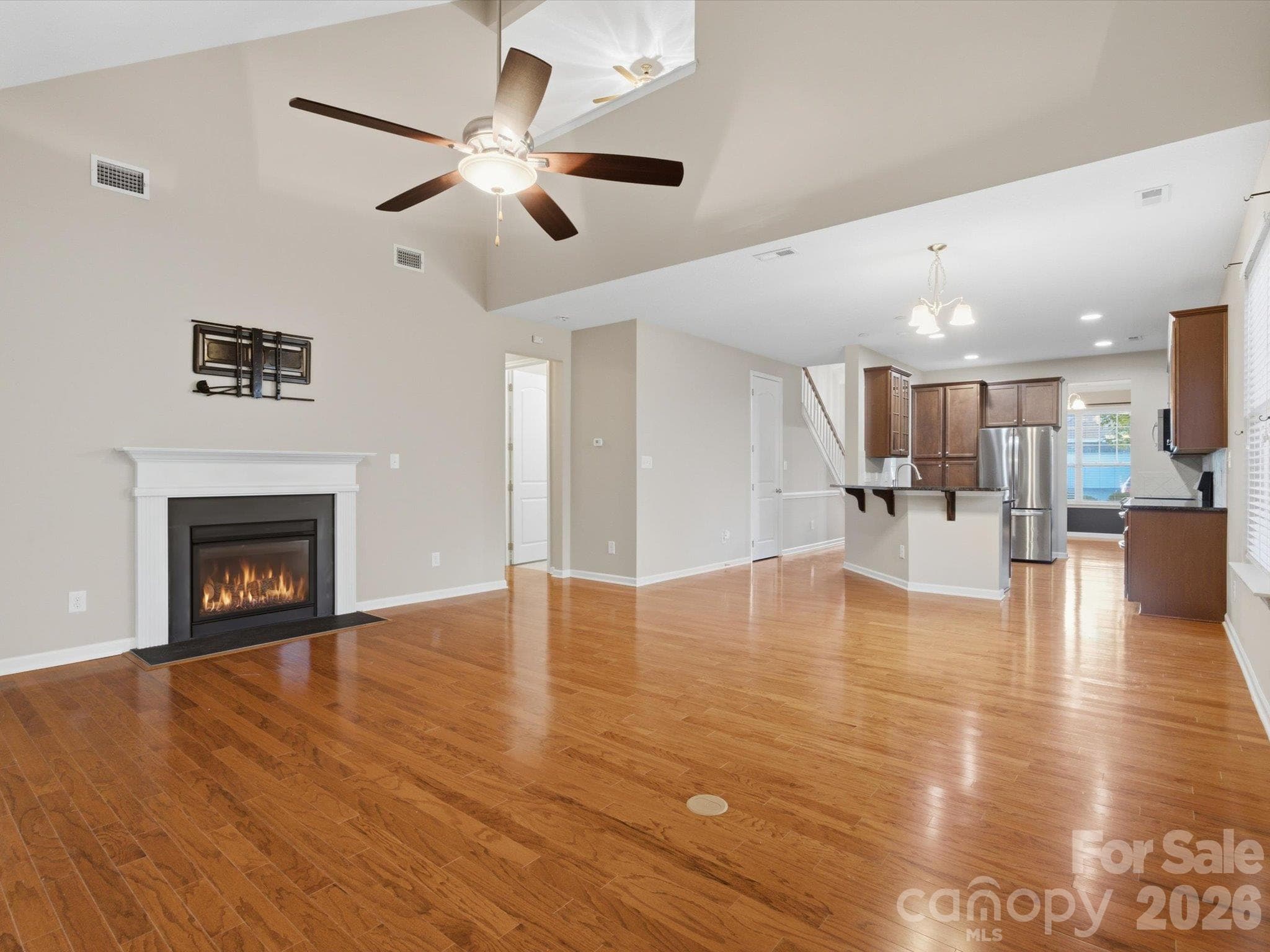 Living room with vaulted ceilings, open to the kitchen, screened-in porch, and Trex deck. - 15110 Reminisce Lane, Charlotte