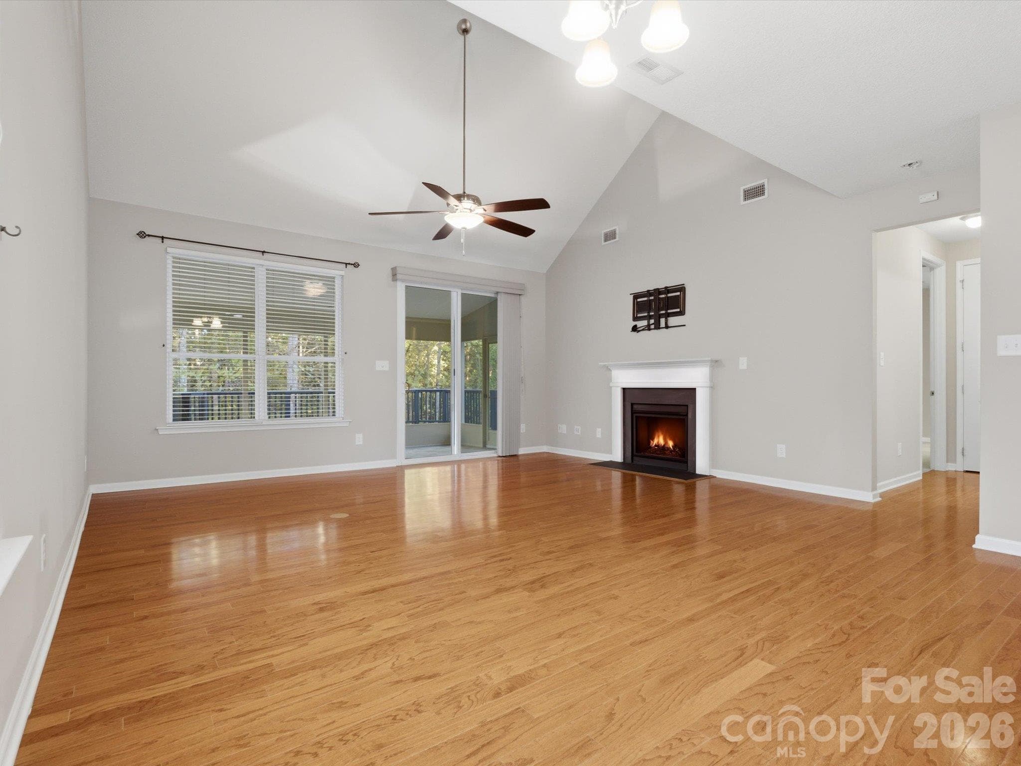 Living room with vaulted ceilings, open to the kitchen, screened-in porch, and Trex deck. - 15110 Reminisce Lane, Charlotte