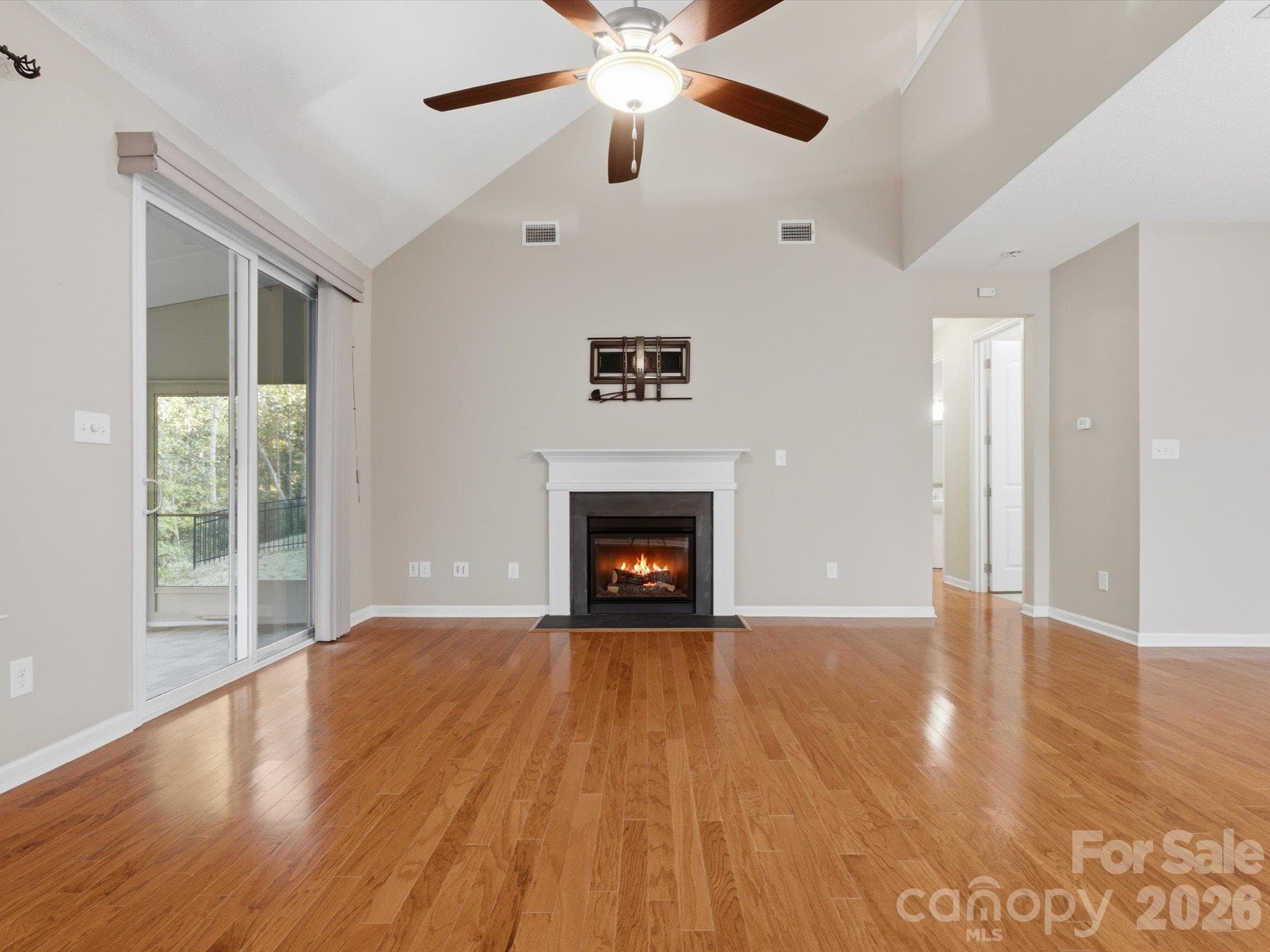 Living room with vaulted ceilings, open to the kitchen, screened-in porch, and Trex deck. - 15110 Reminisce Lane, Charlotte