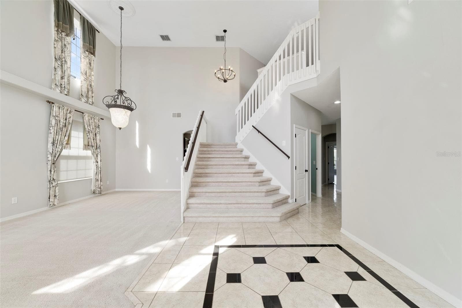 Inside, ETCHED-GLASS FRENCH DOORS open to a welcoming foyer with a SOARING CEILING and decorative tile flooring, setting the stage for the generous living spaces beyond. - 1557 AMARYLLIS CIR, ORLANDO