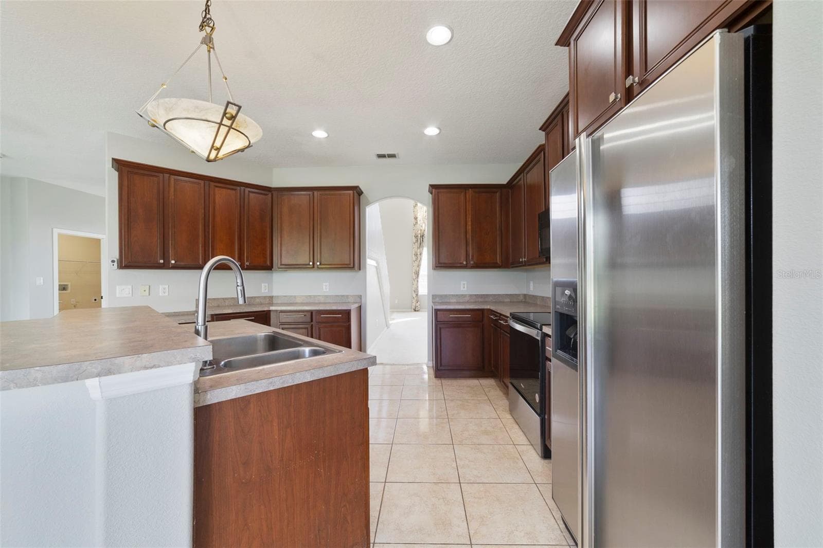 Step through an arched doorway into the spacious Kitchen with ABUNDANT STAGGERED CABINETRY and generous counter space. - 1557 AMARYLLIS CIR, ORLANDO