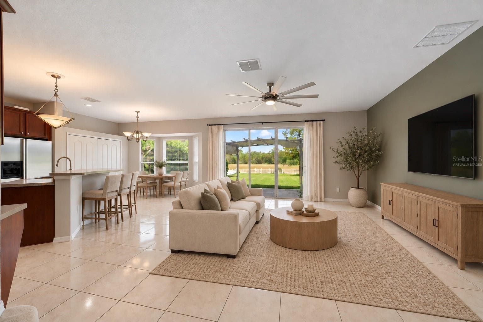The Kitchen flows seamlessly into the Family Room, where triple sliding glass doors bring in NATURAL LIGHT and open to the back patio, extending the living space outdoors. Virtually Staged - 1557 AMARYLLIS CIR, ORLANDO