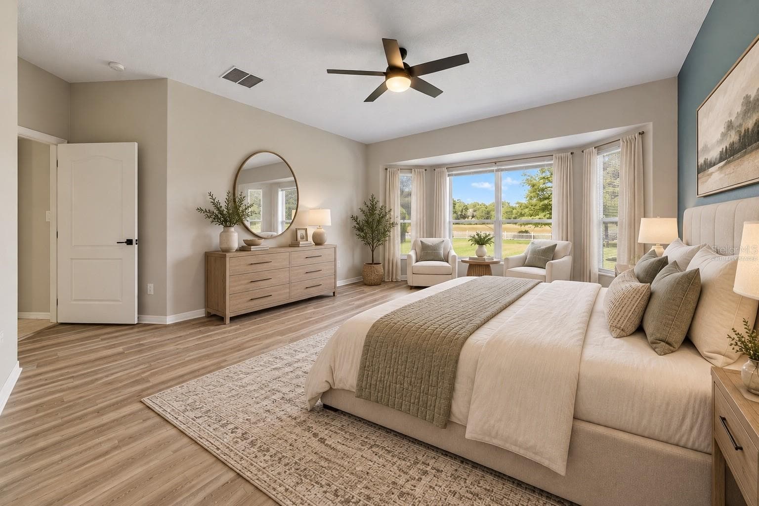 The FIRST-FLOOR PRIMARY SUITE presents a private retreat with LVP FLOORING and a bay window that fills the room with NATURAL LIGHT. Virtually Staged - 1557 AMARYLLIS CIR, ORLANDO