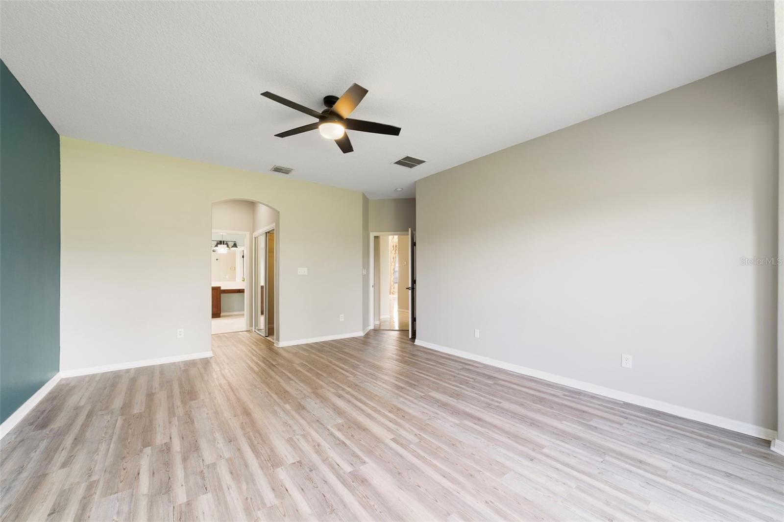 The FIRST-FLOOR PRIMARY SUITE presents a private retreat with LVP FLOORING and a bay window that fills the room with NATURAL LIGHT. - 1557 AMARYLLIS CIR, ORLANDO