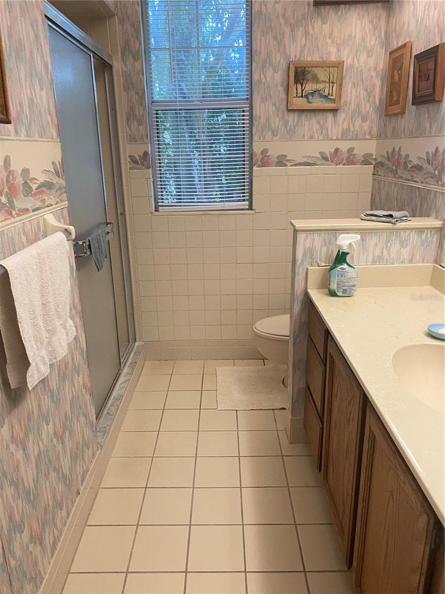 Guest bathroom, narrow window, walk-in showder wallpaaper on the walls. - 11492 SW 82ND COURT RD, OCALA
