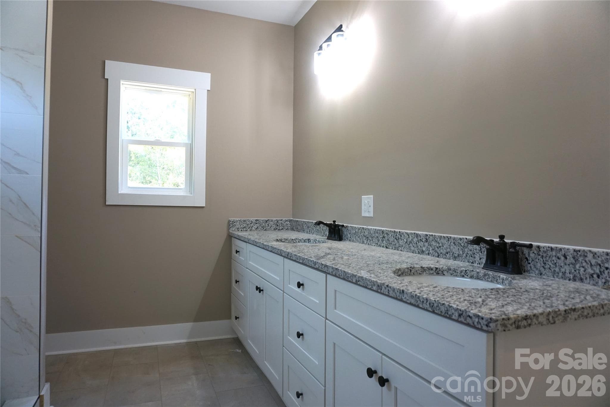 Primary bath with double sink vanity and a view of the back yard. - 989 Rhyne Road, Clover