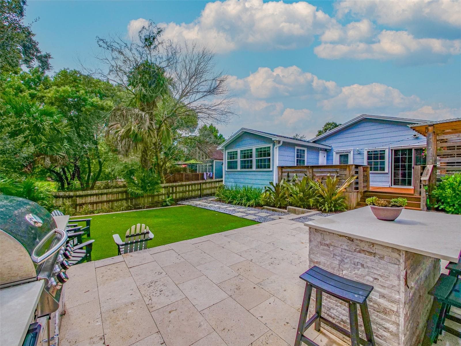 View from the outdoor kitchen across the patio and turf to the rear exterior - 11 S LAWSONA BLVD, ORLANDO