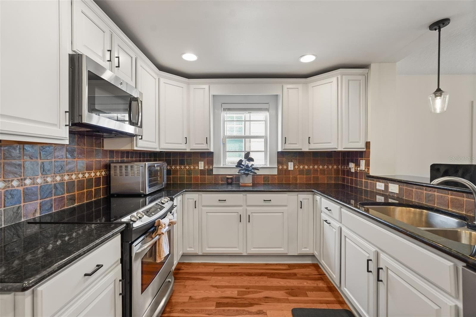 Kitchen with white cabinetry, stainless steel appliances, and tile backsplash - 11 S LAWSONA BLVD, ORLANDO