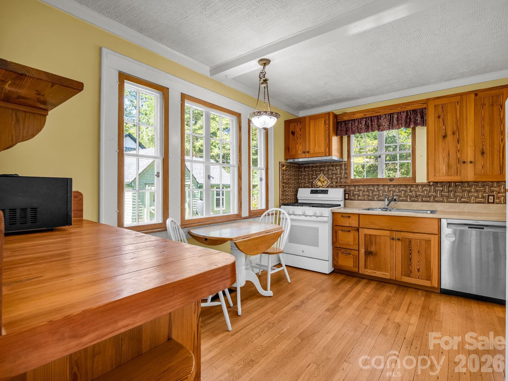 The inviting kitchen features heart-pine cabinetry, a custom butcher-block countertop crafted by Lloyd Nelson, and distinctive tile designed by Jay Reese - 323 Blythe Street, Hendersonville