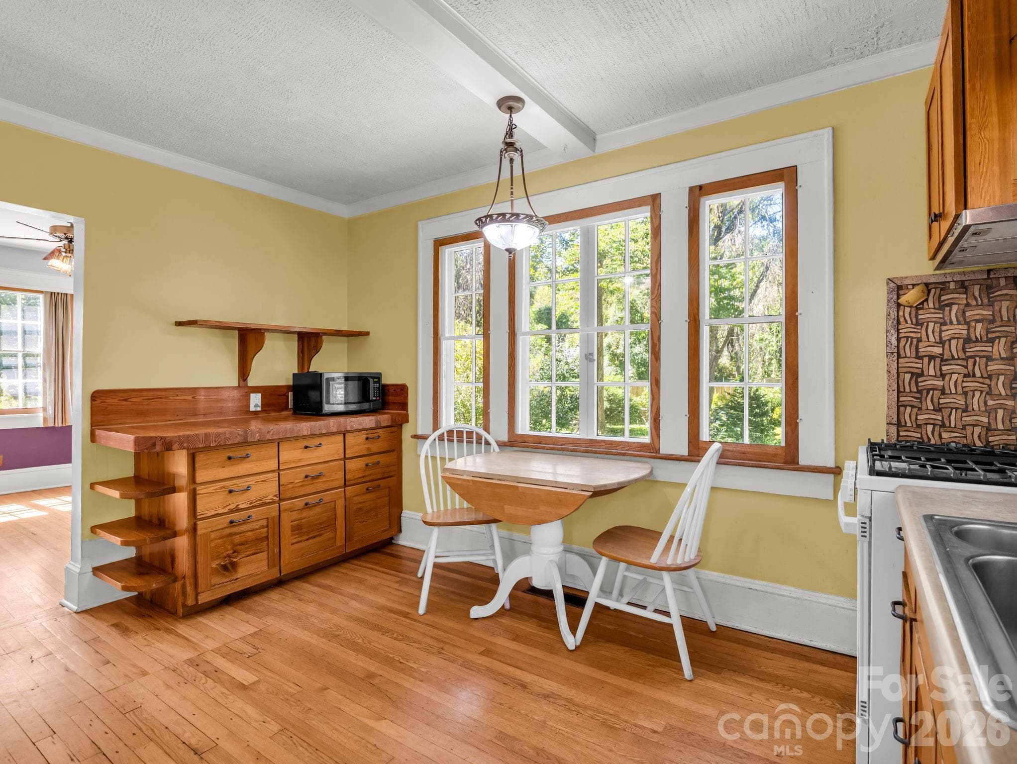 The inviting kitchen features heart-pine cabinetry, a custom butcher-block countertop crafted by Lloyd Nelson, and distinctive tile designed by Jay Reese - 323 Blythe Street, Hendersonville