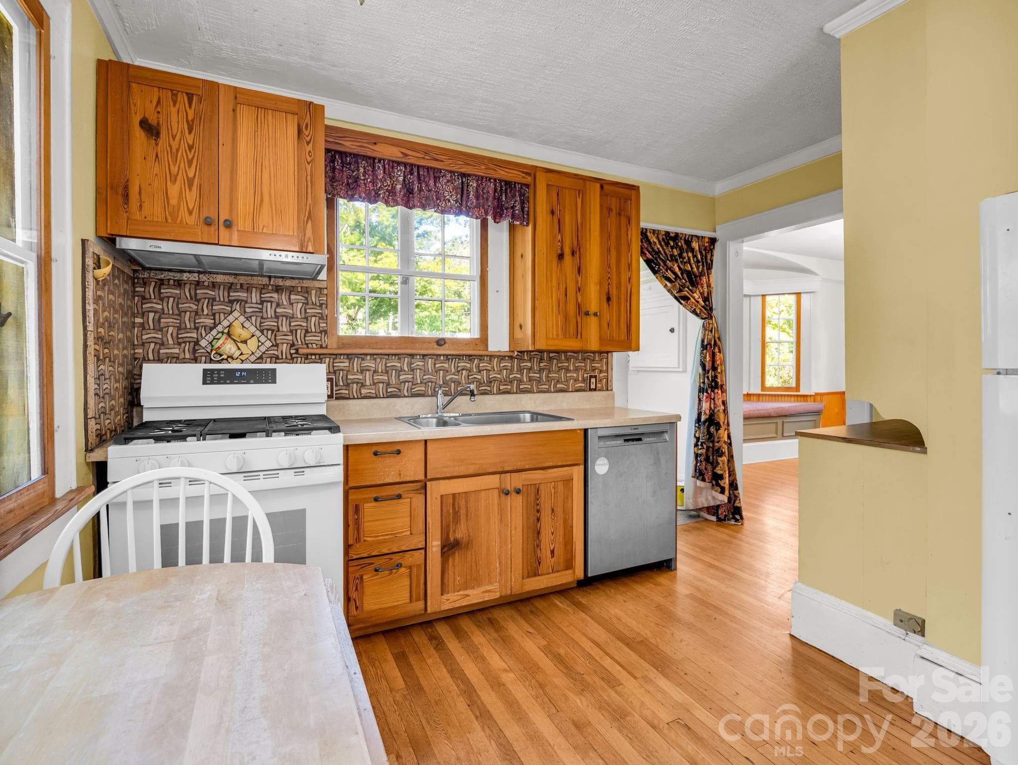 The inviting kitchen features heart-pine cabinetry, a custom butcher-block countertop crafted by Lloyd Nelson, and distinctive tile designed by Jay Reese - 323 Blythe Street, Hendersonville