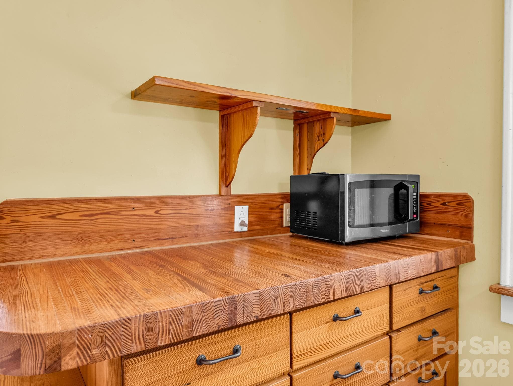 The inviting kitchen features heart-pine cabinetry, a custom butcher-block countertop crafted by Lloyd Nelson, and distinctive tile designed by Jay Reese - 323 Blythe Street, Hendersonville