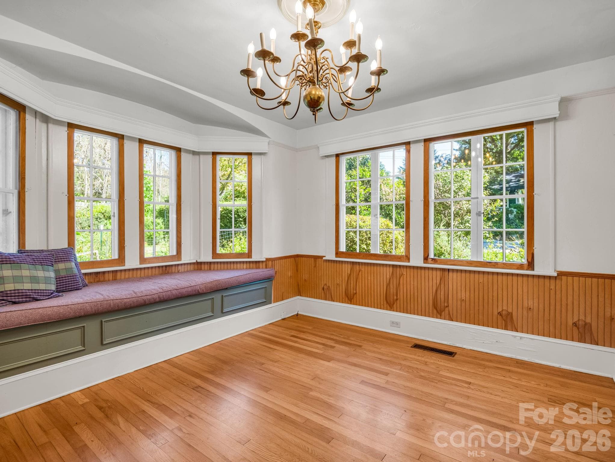 Formal dining room with a bay window and storage seating, beautiful chandelier - 323 Blythe Street, Hendersonville
