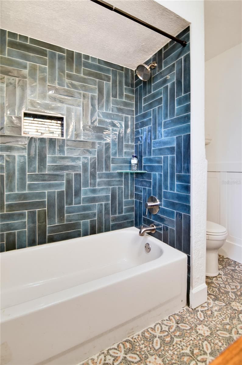 Beautifully tiled bathtub and shower combination with striking blue/green accent tile. - 1611 CHESTNUT AVE, WINTER PARK
