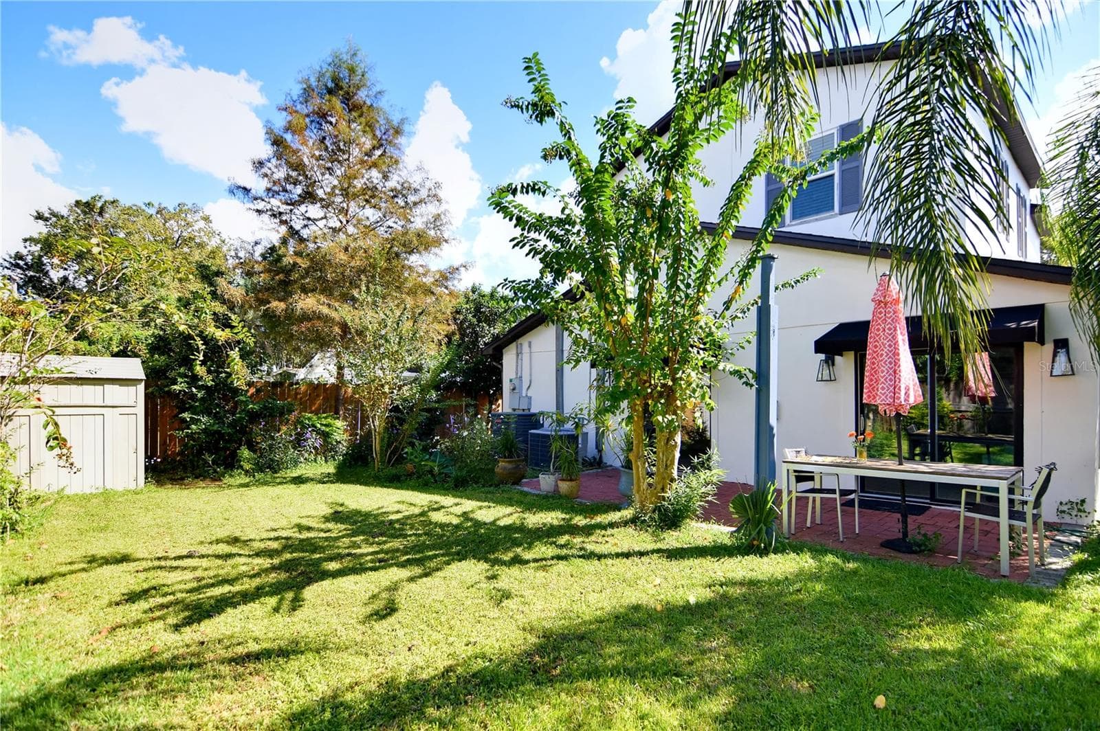 Expansive backyard with mature palms, green lawn, and views of the home's rear exterior. - 1611 CHESTNUT AVE, WINTER PARK