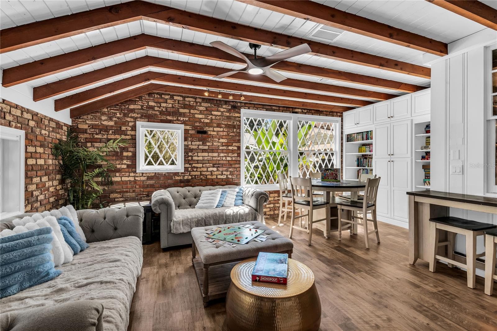 Natural light pours into the spacious family room that features warm brick walls, exposed wood beams and distinctive diamond-pane windows that create a timeless architectural backdrop. - 234 N LAKEVIEW AVE, WINTER GARDEN