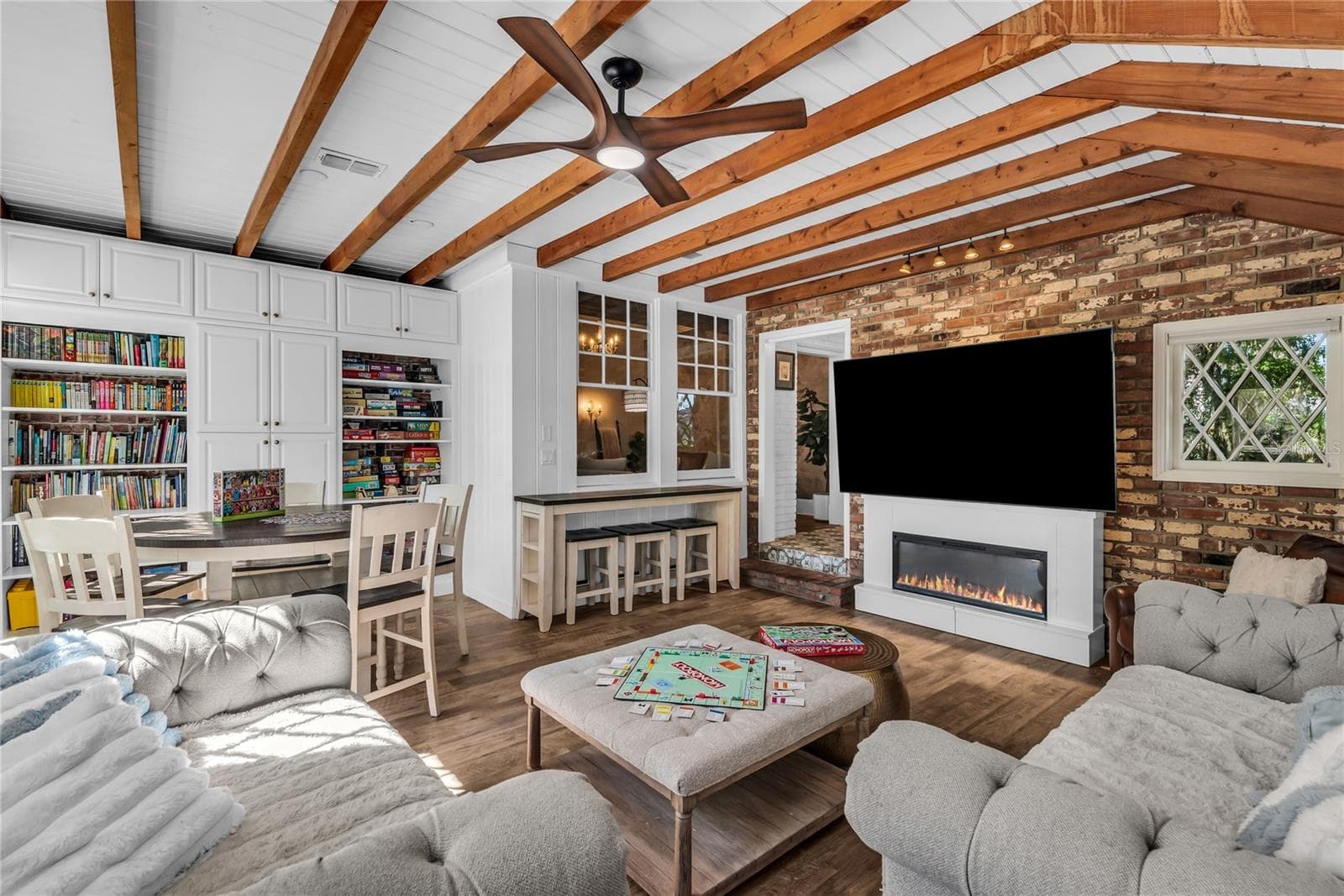 Natural light pours into the spacious family room that features warm brick walls, exposed wood beams and distinctive diamond-pane windows that create a timeless architectural backdrop. - 234 N LAKEVIEW AVE, WINTER GARDEN