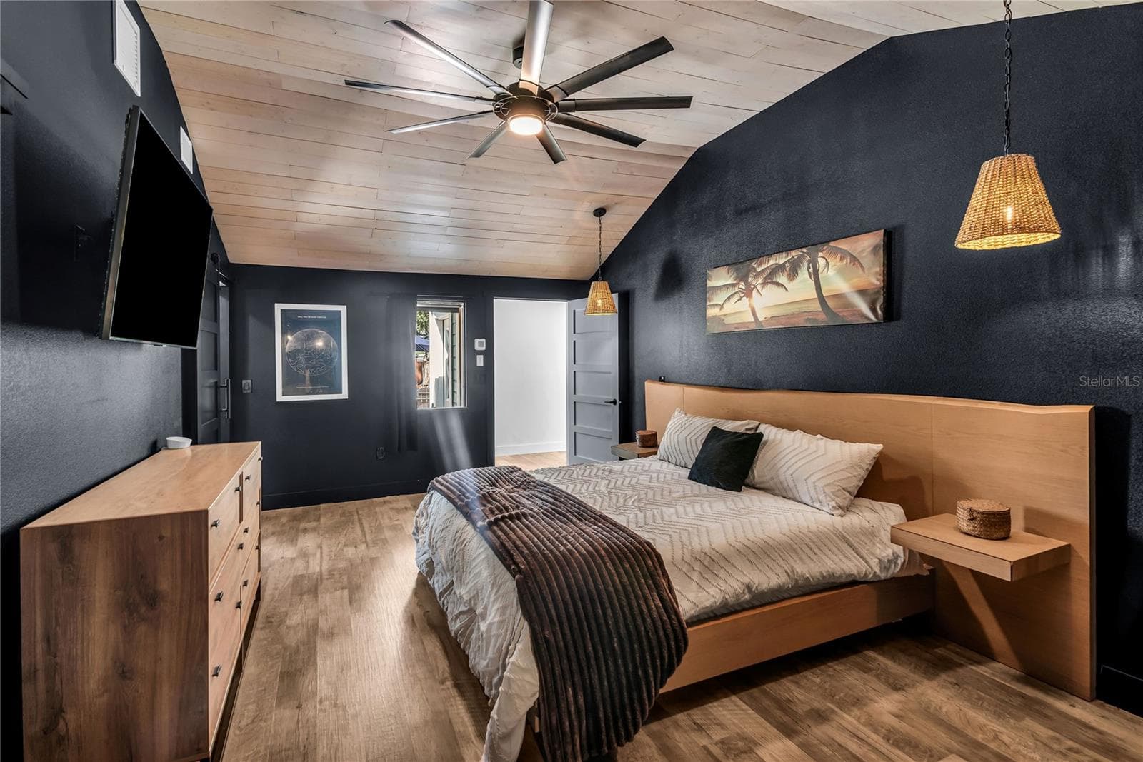 The secluded primary suite blends modern design with inviting comfort, showcasing a striking vaulted plank ceiling, stylish pendant lighting, and an expansive layout. Thoughtfully positioned for privacy, this retreat feels both intimate and spacious, with warm wood accents and sophisticated finishes creating a refined yet relaxing atmosphere. - 234 N LAKEVIEW AVE, WINTER GARDEN
