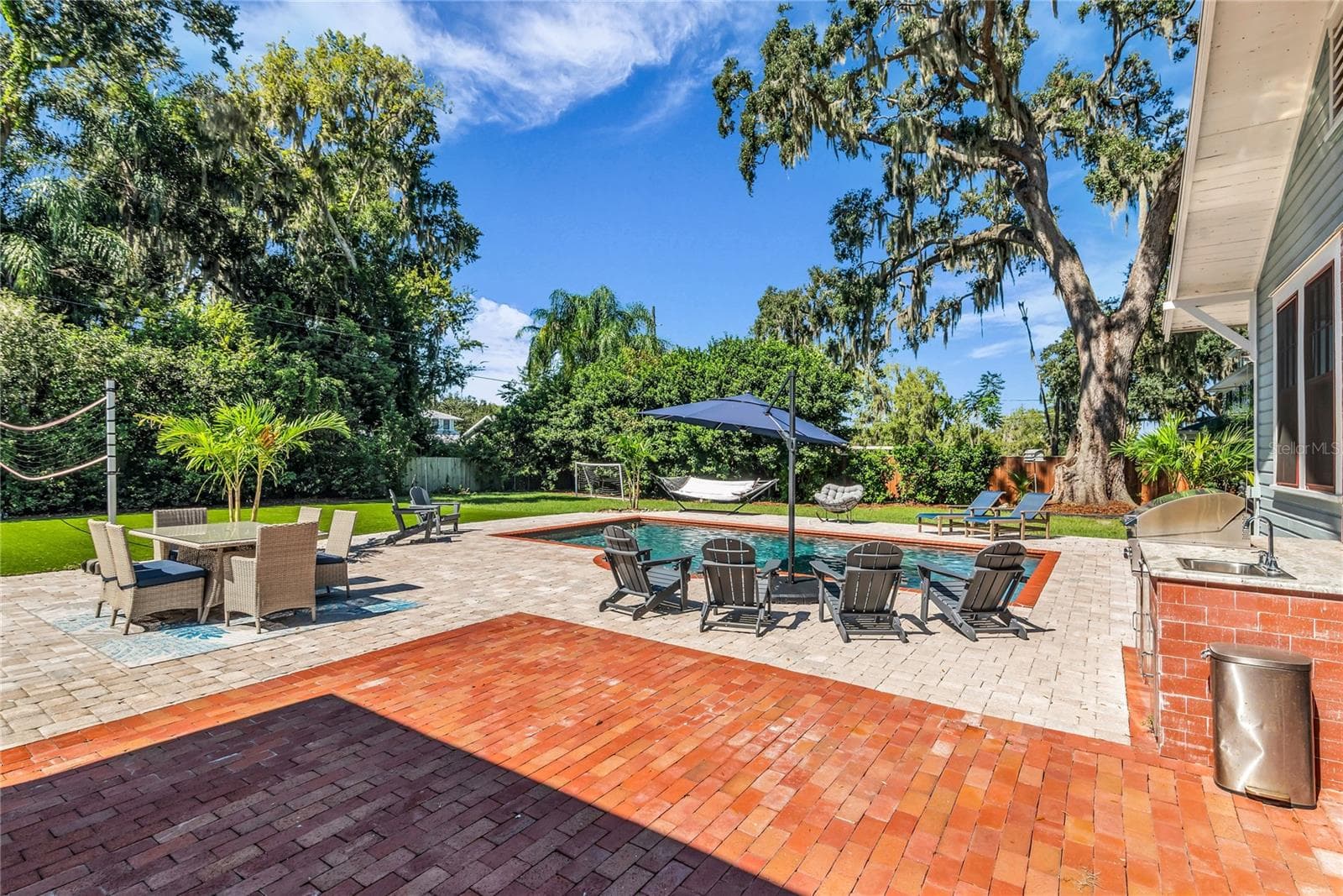 The enormous fully fenced backyard is designed for year-round enjoyment with a gas-heated saltwater sport pool, outdoor kitchen, expansive brick paved deck, detached covered lanai, and low-maintenance turf. - 234 N LAKEVIEW AVE, WINTER GARDEN