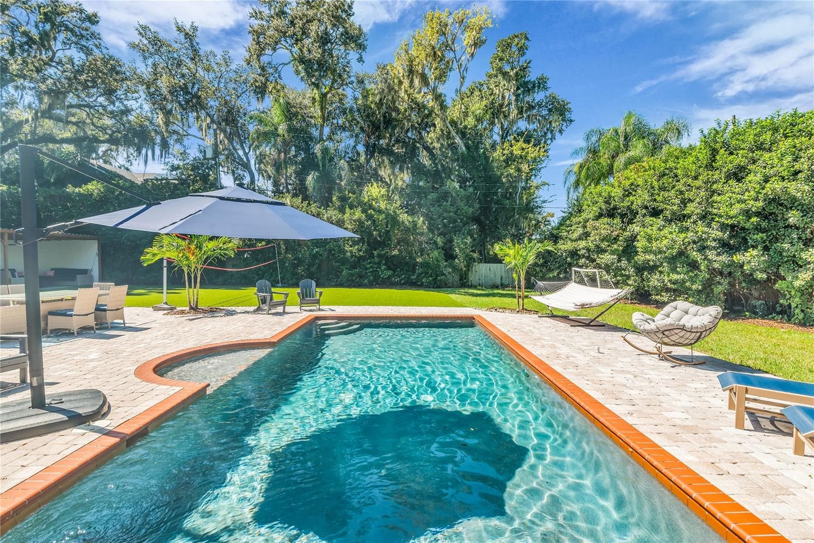 The enormous fully fenced backyard is designed for year-round enjoyment with a gas-heated saltwater sport pool, outdoor kitchen, expansive brick paved deck, detached covered lanai, and low-maintenance turf. - 234 N LAKEVIEW AVE, WINTER GARDEN