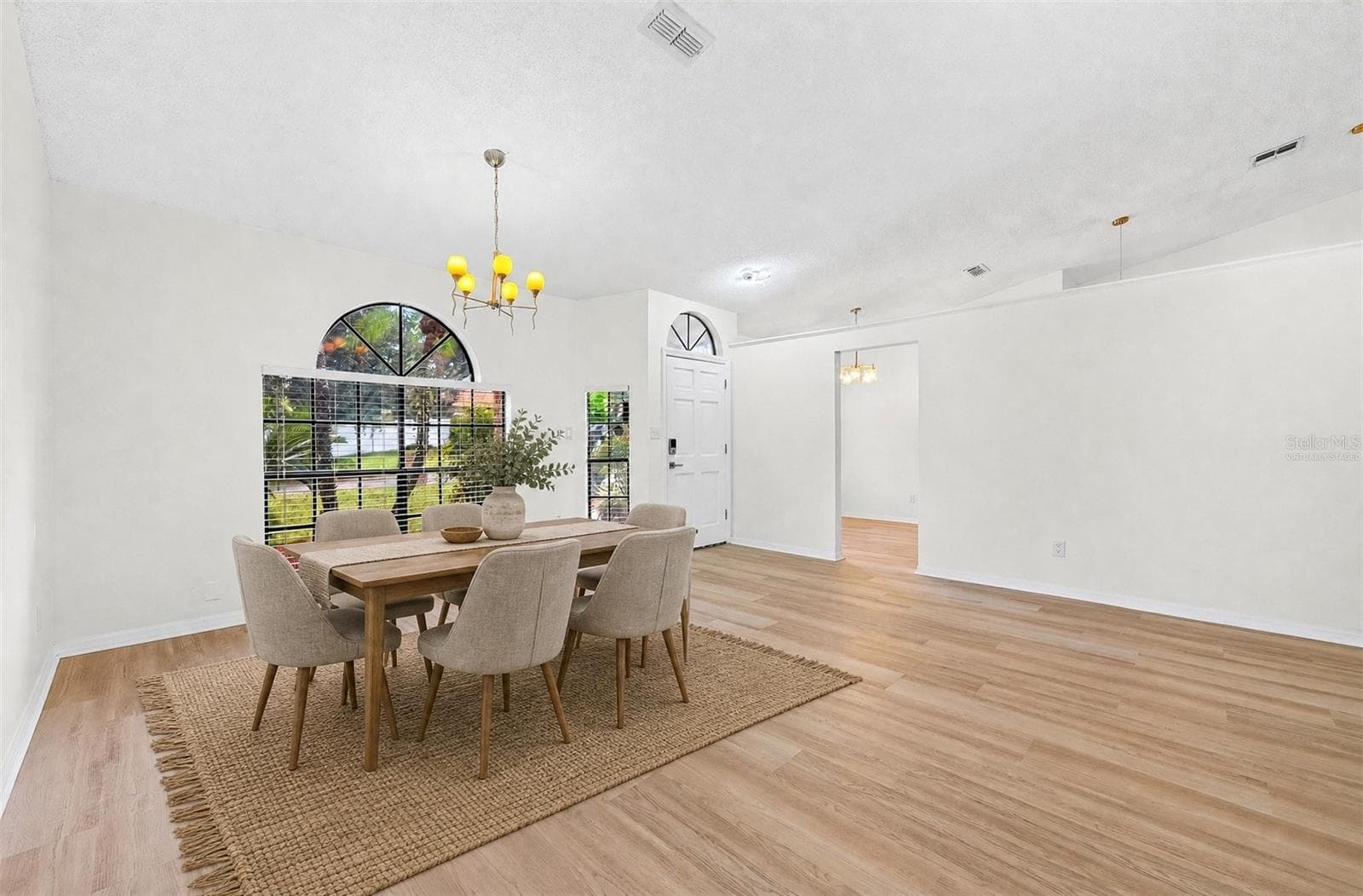 The formal Dining Room features an ELEGANT ARCHED LUNETTE WINDOW and flows into the Living Room. Virtually Staged - 1003 N MAGEE CREEK CT, OVIEDO