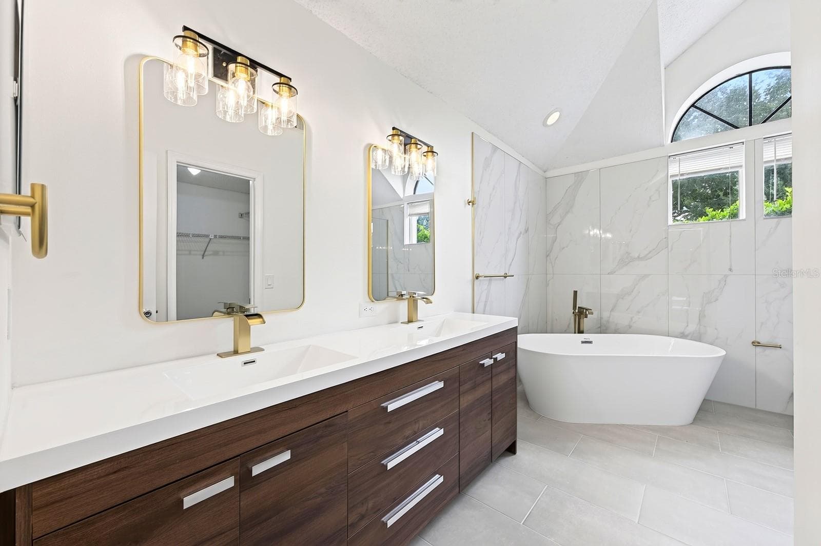 The Primary en suite Bath has been COMPLETELY UPDATED IN 2026 with dual sinks, a garden tub, a step-in shower and stylish MARBLE-LOOK tile walls. - 1003 N MAGEE CREEK CT, OVIEDO