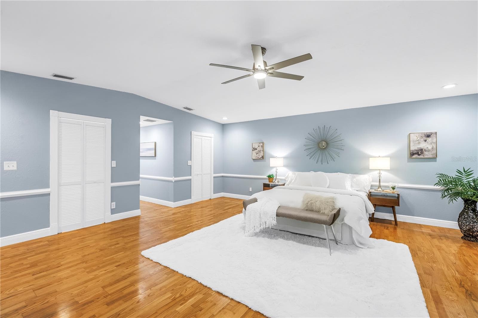 Exquisite primary bedroom suite featuring dual expansive walk-in closets, vaulted ceilings, a dedicated sitting area, hardwood flooring, and a private en suite bathroom. - 146 GIRALDA BLVD NE, ST PETERSBURG