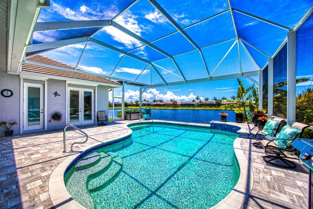 Screen lanai with picture window to lake in 2022 - 8625 SOUTHWIND BAY CIR, FORT MYERS