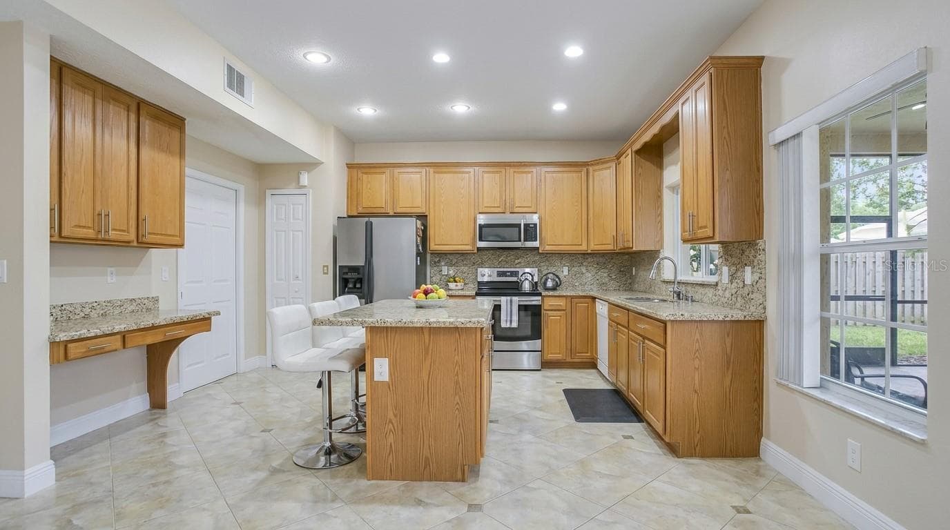 Spacious kitchen view from the dining room, featuring modern finishes and an open-concept layout. - 7866 BARDMOOR HILL CIR, ORLANDO