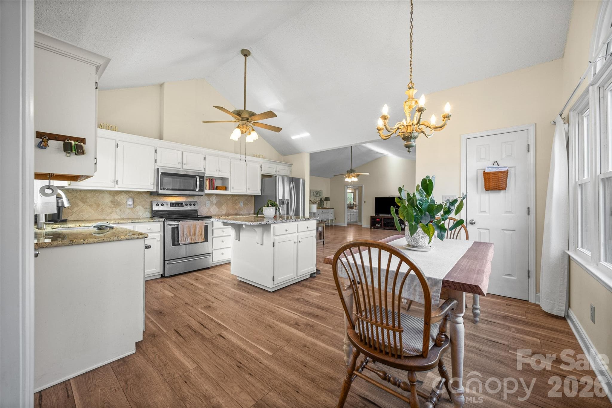 Open kitchen with island and granite countertops. Plank flooring throughout. - 3117 Monte Drive, Monroe