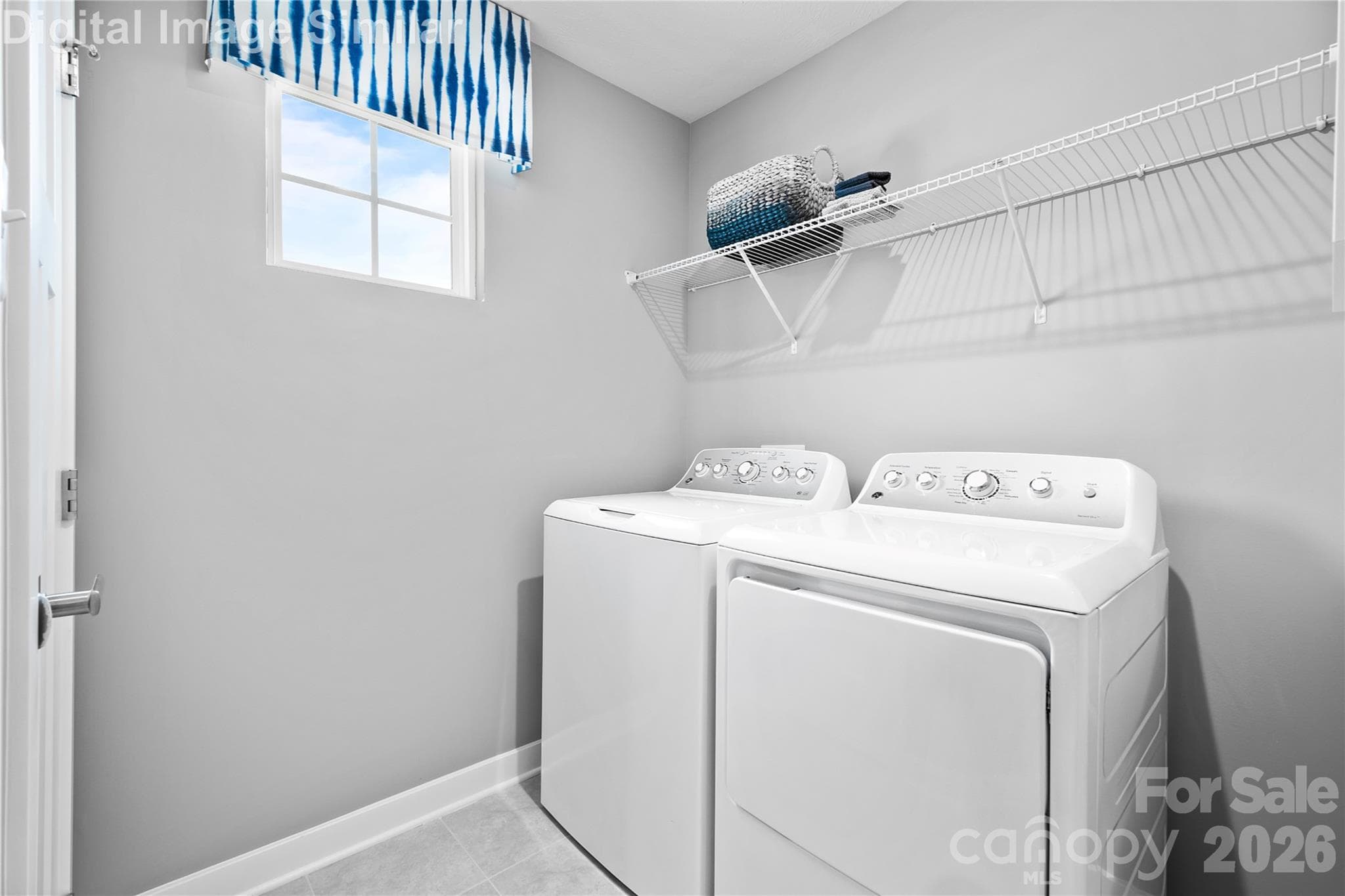 Walk-in laundry room with a bright window, built-in shelving for detergents and towels—just toss in a load and close the door for quiet convenience. - 11204 Emerson Landing Drive, Charlotte