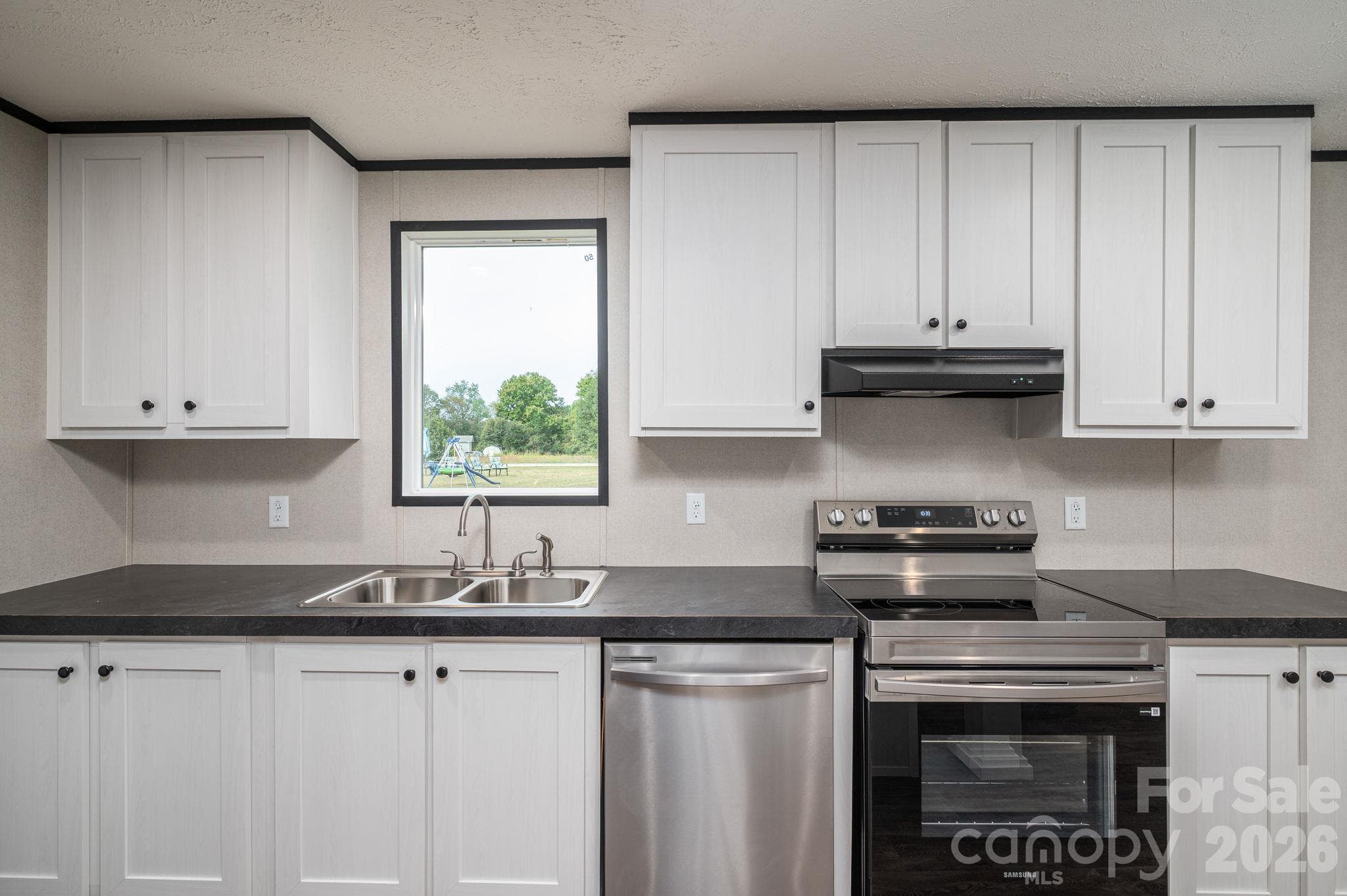 Kitchen with dark accent counter tops and stainless appliances - 207 Grassy Field Court, Lawndale