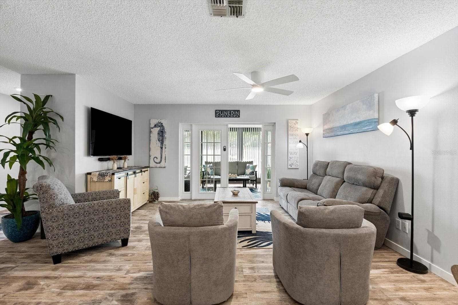 Living room with LVP flooring opens to enclosed Lanai - 1307 STONEHAVEN LN, DUNEDIN