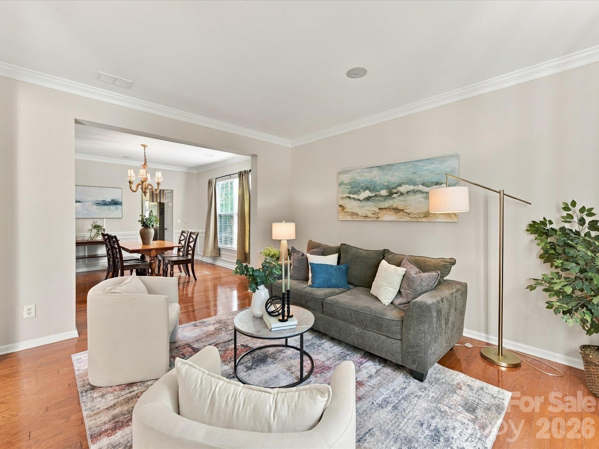 Spacious formal living room featuring rich hardwood floors, elegant crown molding, and an open layout that flows seamlessly into the main living areas, perfect for everyday living and entertaining. - 1788 Oakmont Drive, Denver