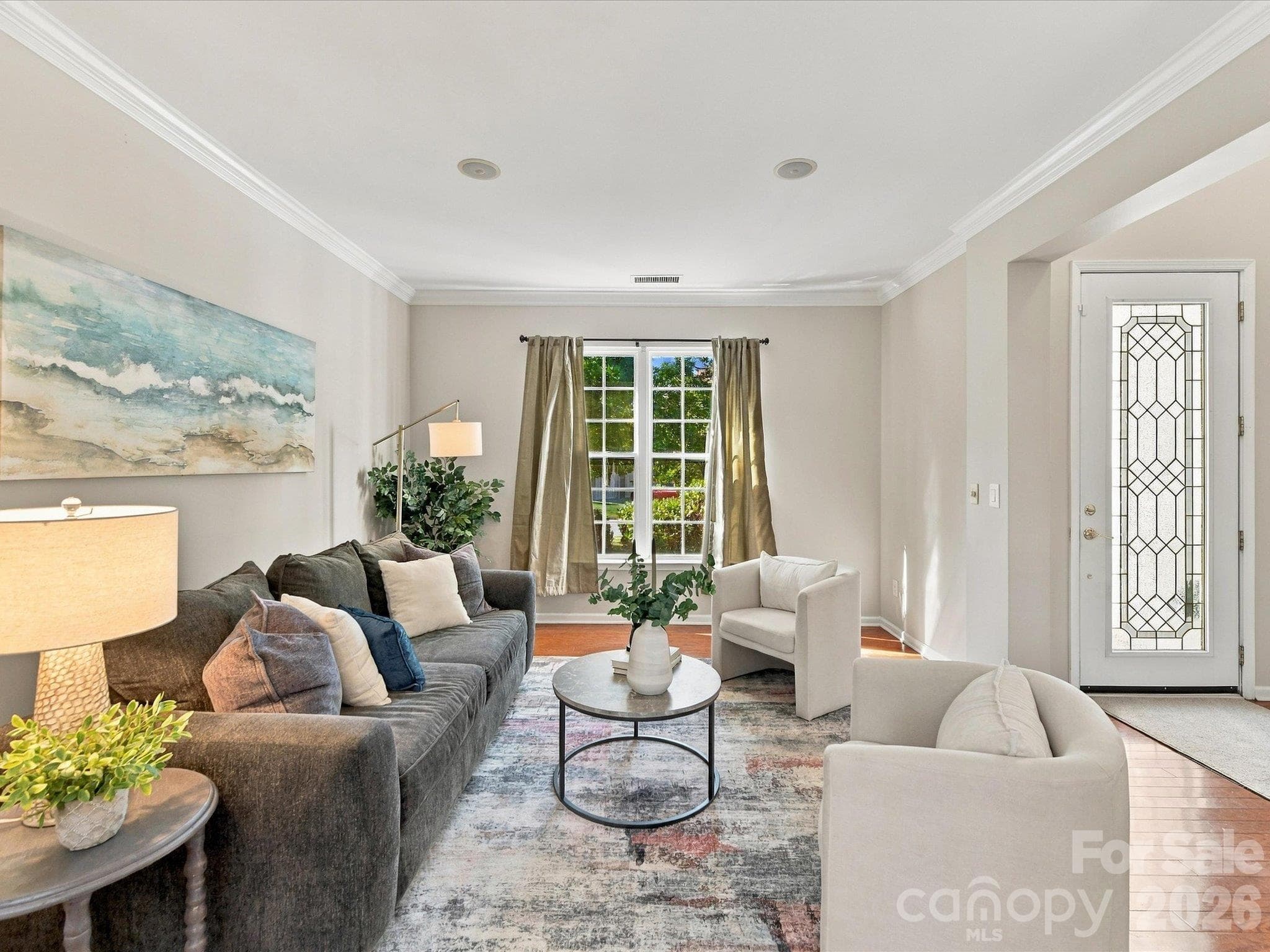 Spacious formal living room featuring rich hardwood floors, elegant crown molding, and an open layout that flows seamlessly into the main living areas, perfect for everyday living and entertaining. - 1788 Oakmont Drive, Denver