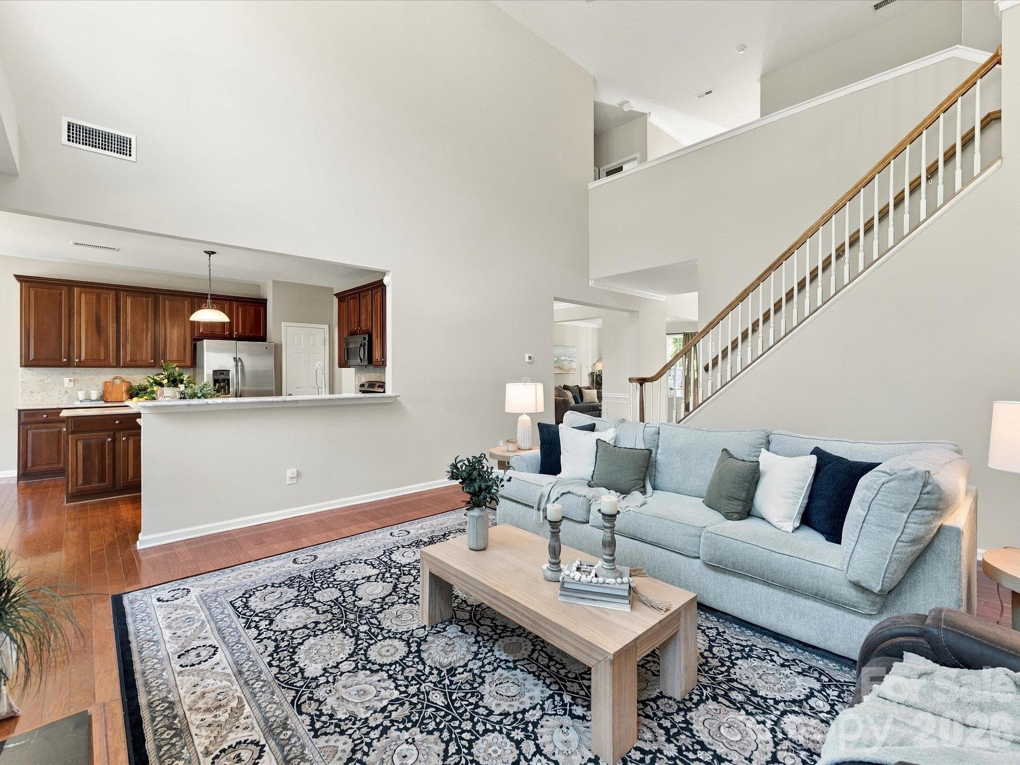 Light-filled living room featuring soaring ceilings, expansive windows, rich hardwood floors, and a cozy fireplace that creates a warm and inviting gathering space. - 1788 Oakmont Drive, Denver