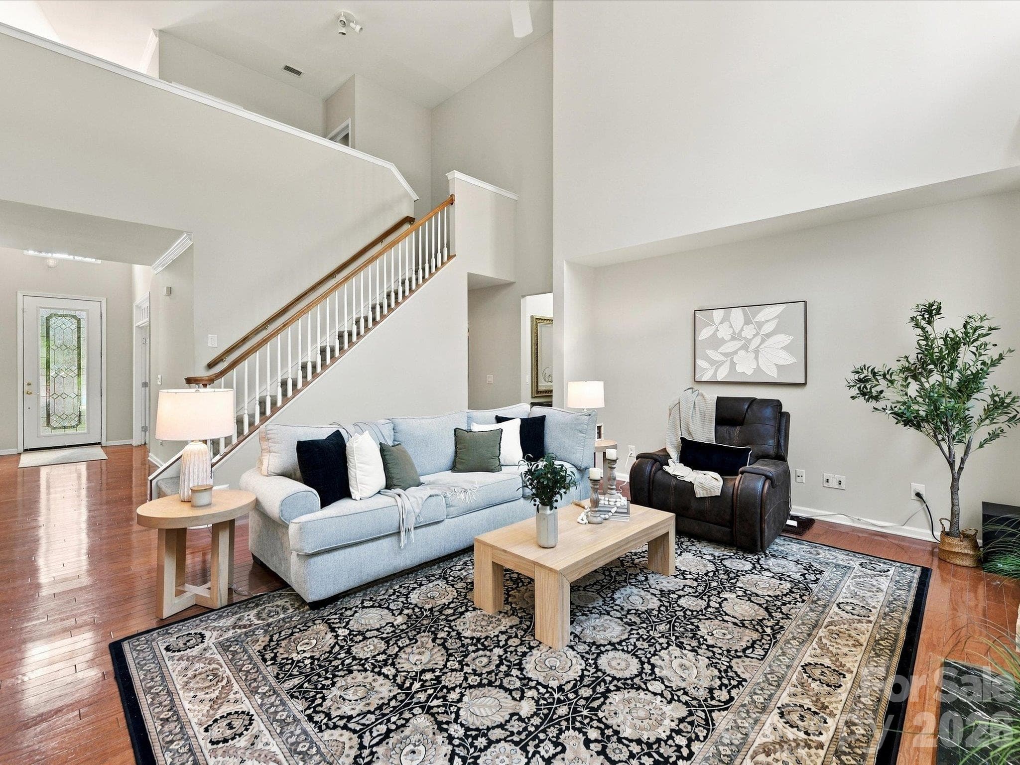 Light-filled living room featuring soaring ceilings, expansive windows, rich hardwood floors, and a cozy fireplace that creates a warm and inviting gathering space. - 1788 Oakmont Drive, Denver