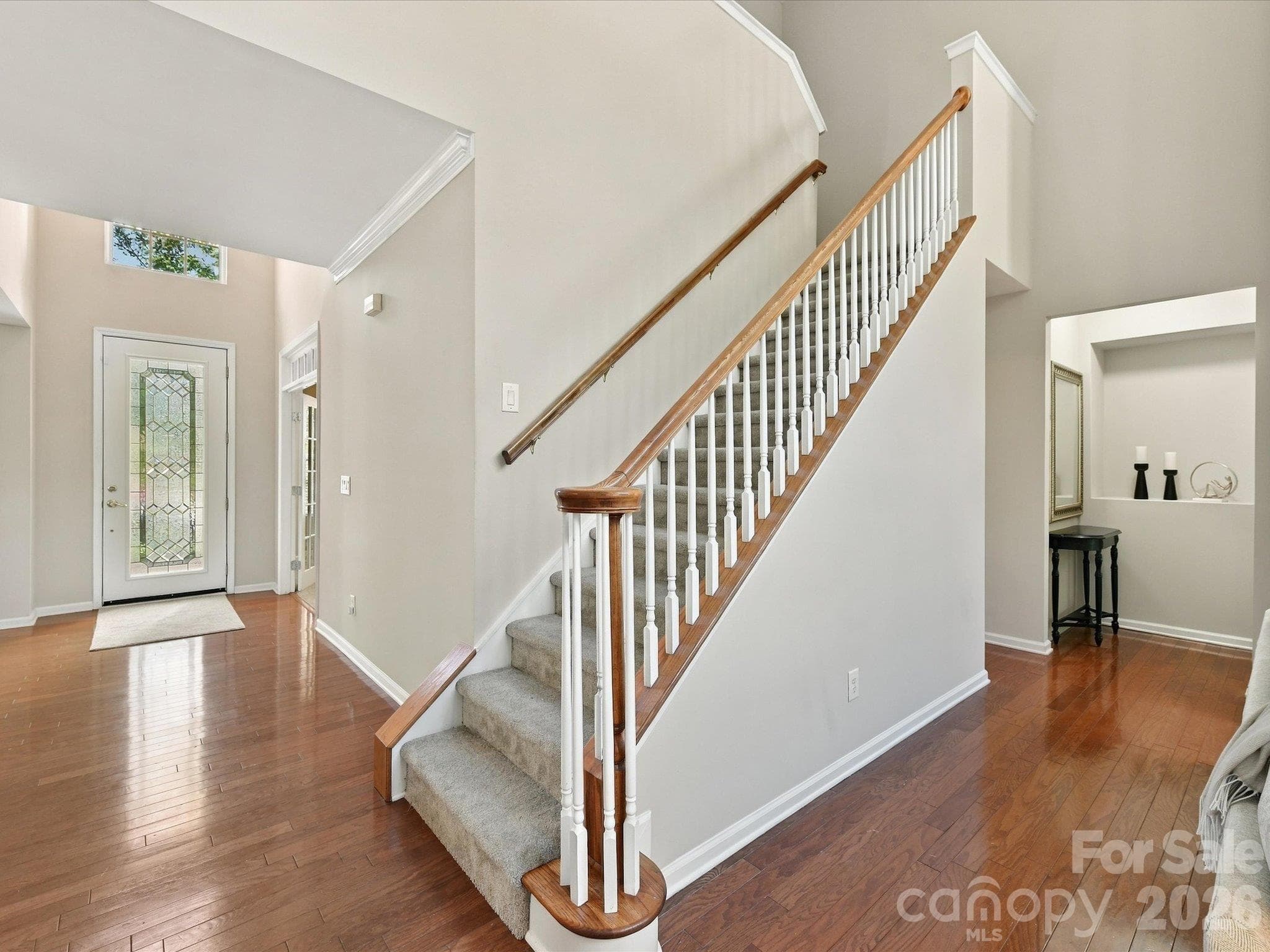 Elegant staircase with classic wood railings overlooks the open living space, creating a seamless flow between levels and enhancing the home's airy feel. - 1788 Oakmont Drive, Denver