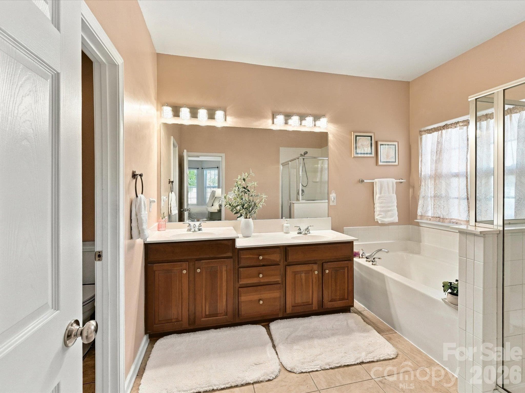 Spa-like primary bathroom featuring a dual-sink vanity, relaxing garden tub, separate glass-enclosed shower, and ample space to start and end your day in comfort. - 1788 Oakmont Drive, Denver
