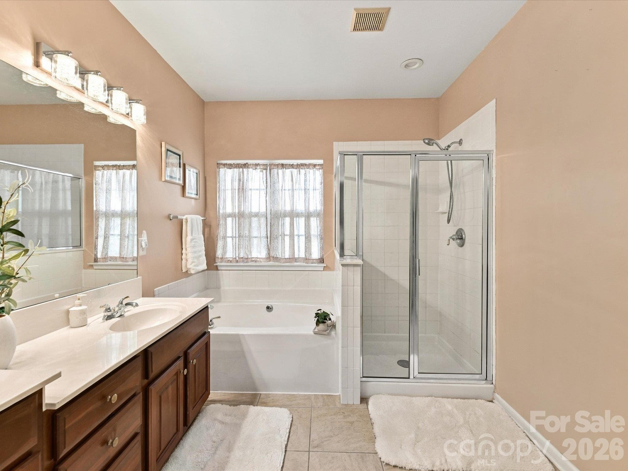 Spa-like primary bathroom featuring a dual-sink vanity, relaxing garden tub, separate glass-enclosed shower, and ample space to start and end your day in comfort. - 1788 Oakmont Drive, Denver