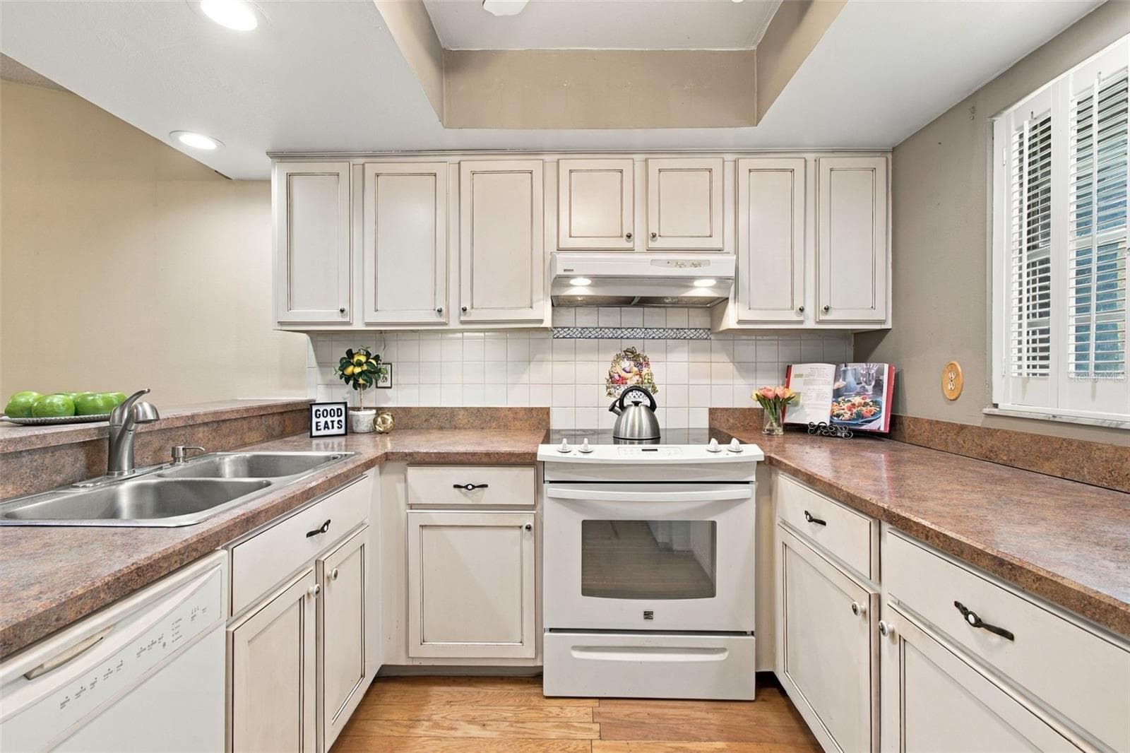 Your home's kitchen features a large window with decorative shutters. - 13020 LEVERINGTON ST, TAMPA