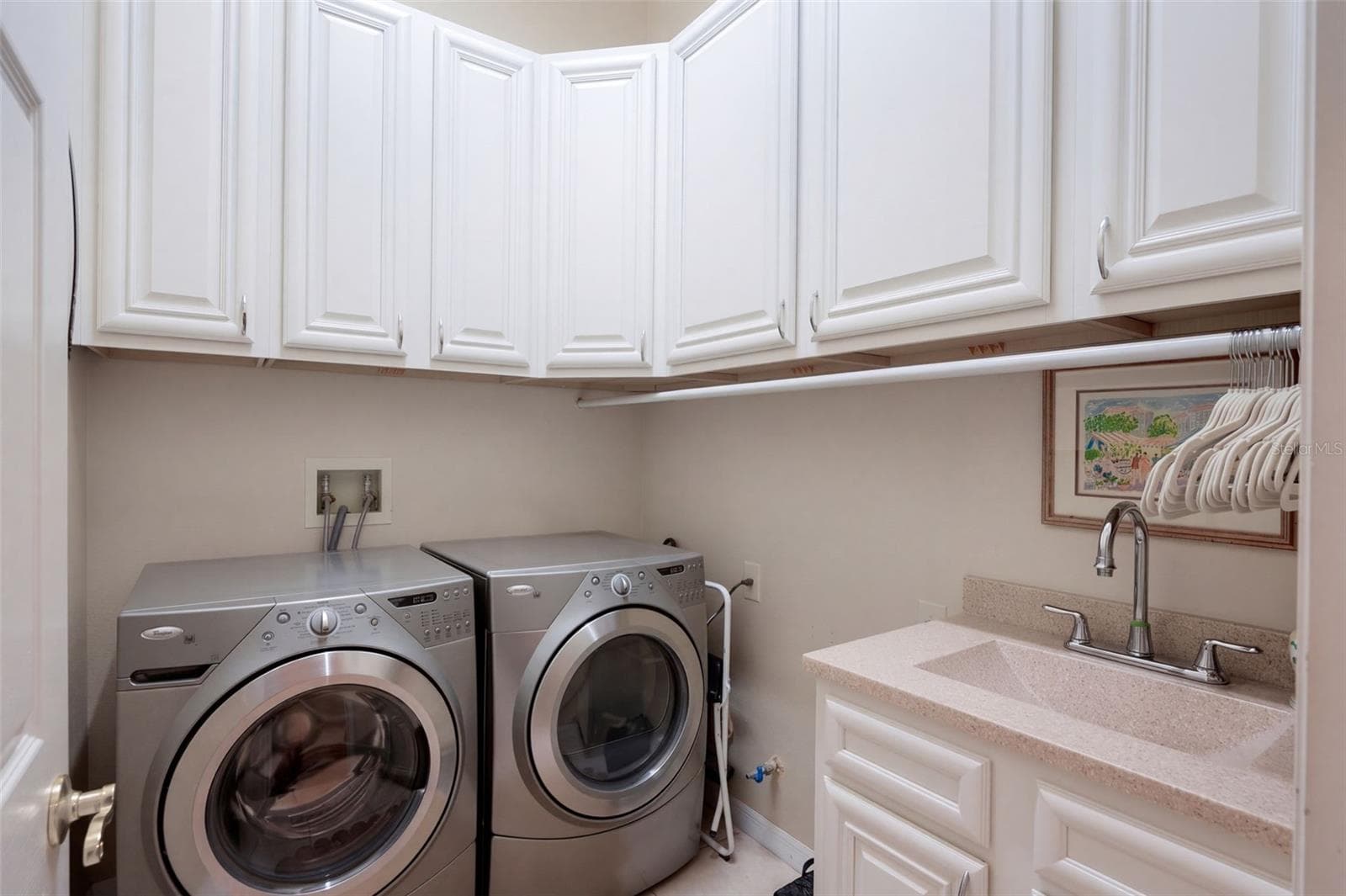 CUSTOM LAUNDRY ROOM FEATURING BEAUTIFUL CABINETRY, AMPLE STORAGE SPACE, AND A CONVENIENT UTILITY SINK FOR ADDED FUNCTIONALITY! - 14542 RIVIERA POINTE DR, ORLANDO